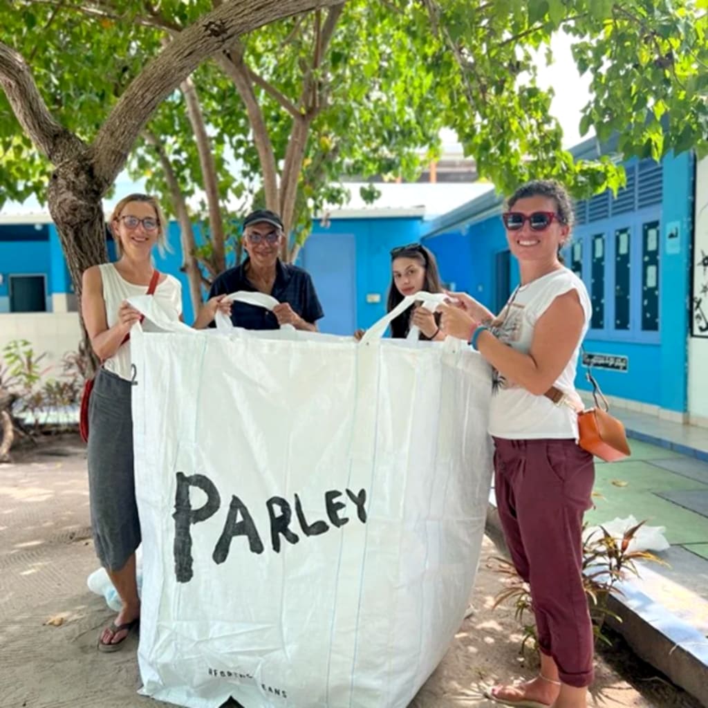 Gruppo di persone con sacco Parley durante attività di pulizia ambientale su un’isola delle Maldive.