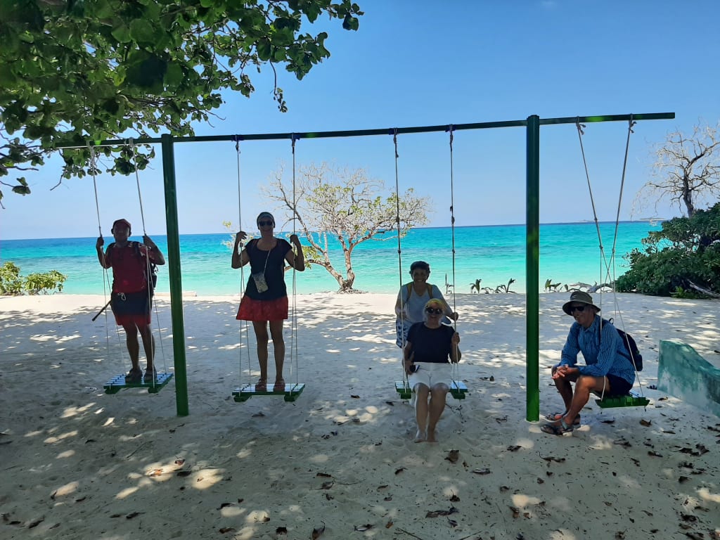 Persone su altalene sulla spiaggia tropicale delle Maldive, momento di relax e divertimento vista oceano