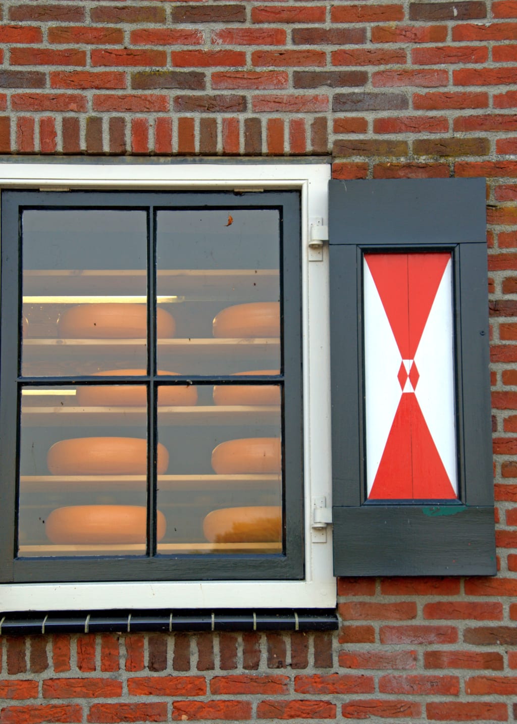 Vetrina con formaggi olandesi in un edificio antico in mattoni.