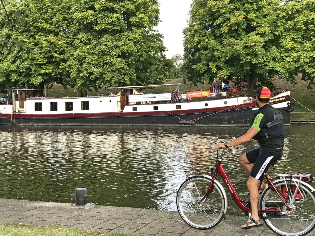 Radfahrer mit Fahrrad auf einem Radweg entlang eines Kanals in den Niederlanden, Girolibero-Radreisen