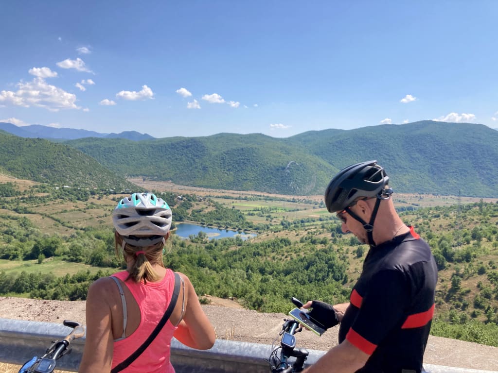 Coppia di cicloturisti che osserva il panorama delle montagne del Parco Nazionale di Llogara lungo la Riviera Albanese
