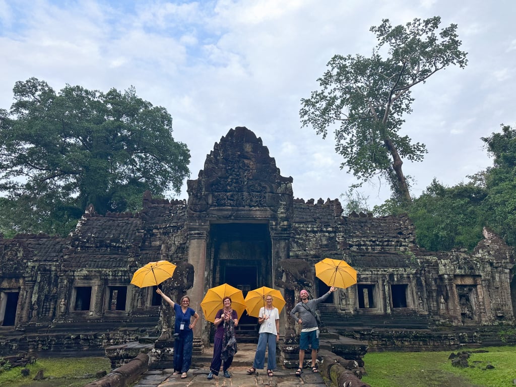 Visitatori con ombrelli gialli davanti al tempio al tramonto, area di Angkor