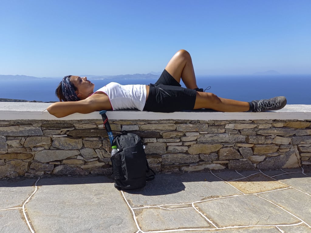 Viaggiatore disteso su una panchina al sole sul lungomare dell'isola di Sifnos, Grecia.