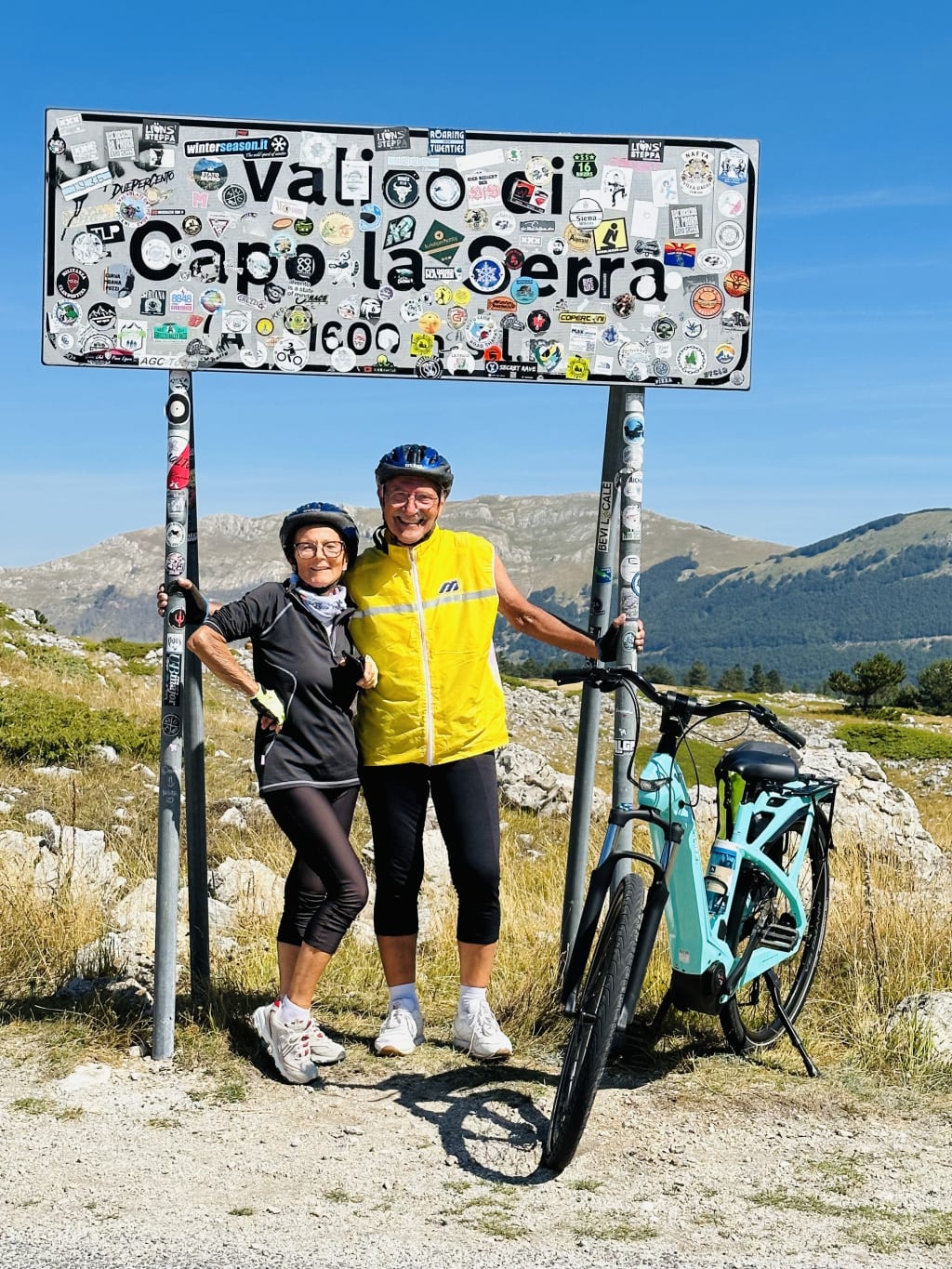 Coppia in bici elettrica fa una foto sotto al cartello "valico di Capo La Serra", Parco Nazionale del Gran Sasso, Abruzzo