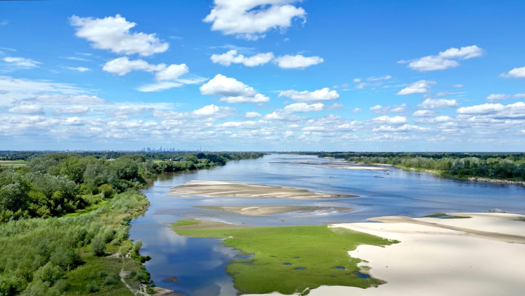 Vista panoramica sul fiume Vistola che attraversa la pianura polacca con cielo sereno e nuvole.