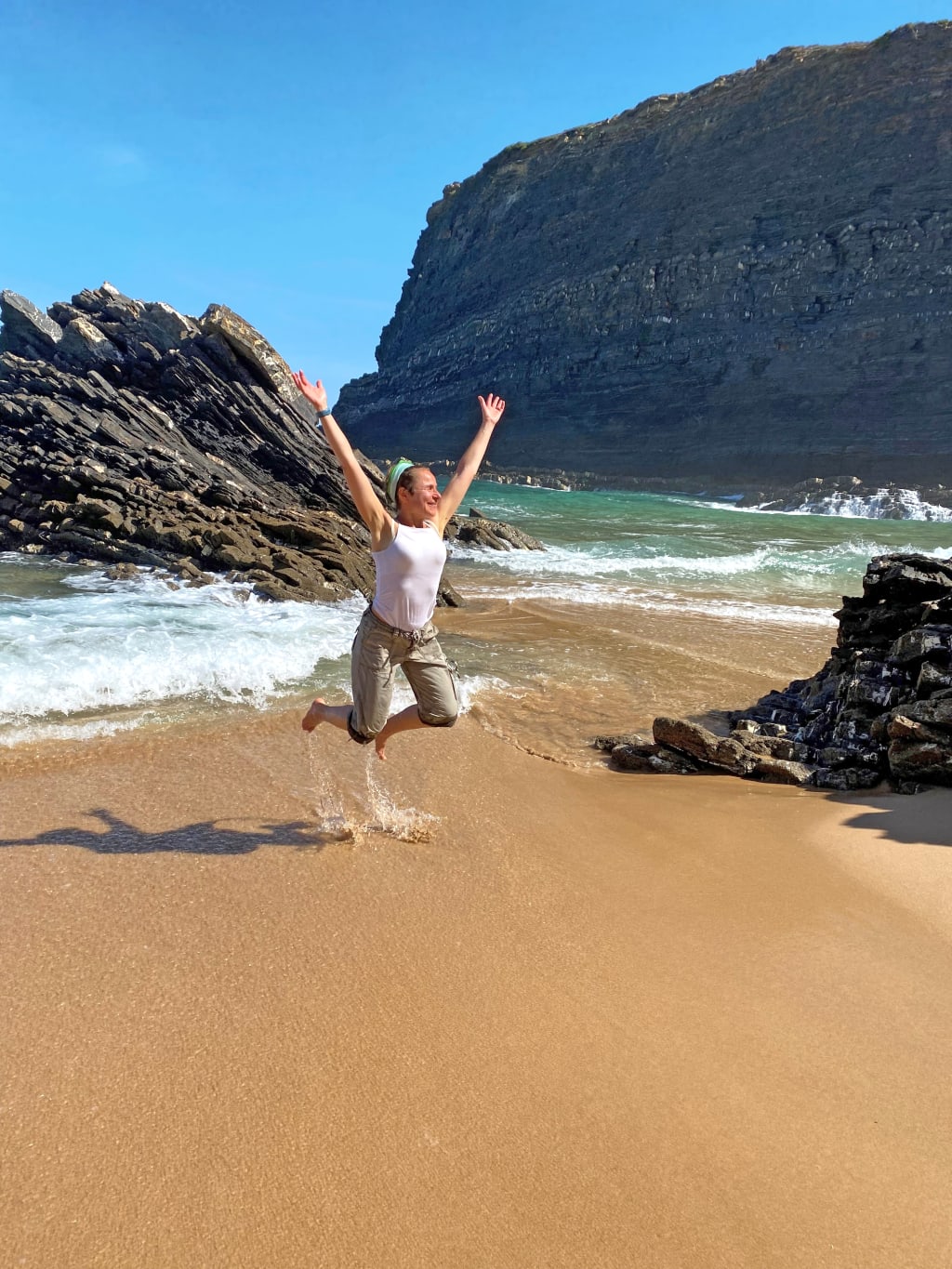 Persona fa una foto sulla spiaggia con una scogliera sulla Rota Vicentina, Algarve