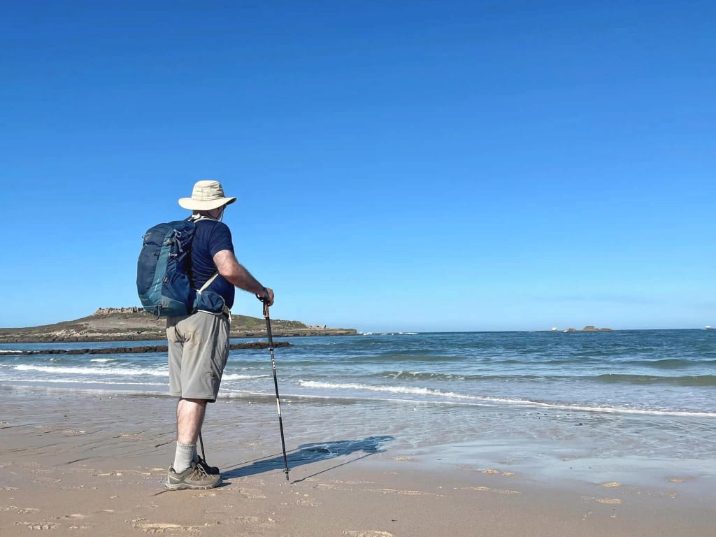 Persona che cammina sulla spiaggia con bastone da trekking lungo la costa portoghese.
