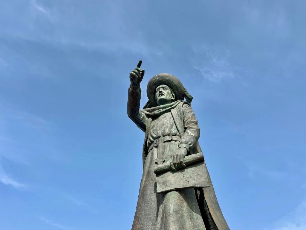 Statua commemorativa in bronzo sotto un cielo azzurro in Portogallo.