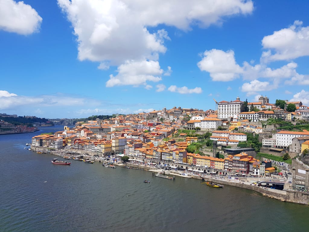 Vista panoramica di una città costiera portoghese lungo il Cammino di Santiago, con case colorate e mare blu.