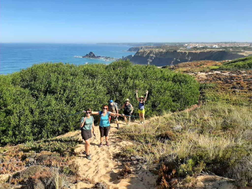 Escursionisti tra la vegetazione costiera della Rota Vicentina, con panorama sul mare in Algarve.