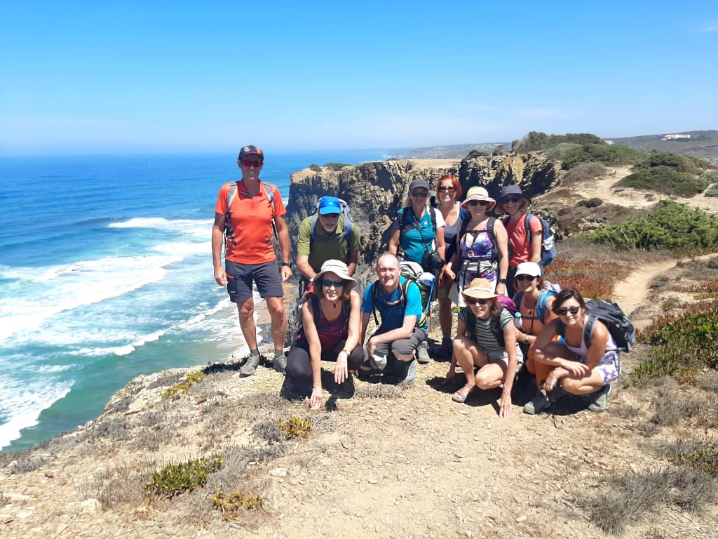 Gruppo di escursionisti in viaggio con "Girolibero" lungo la scogliera con vista sull'oceano lungo la Rota Vicentina, Algarve.