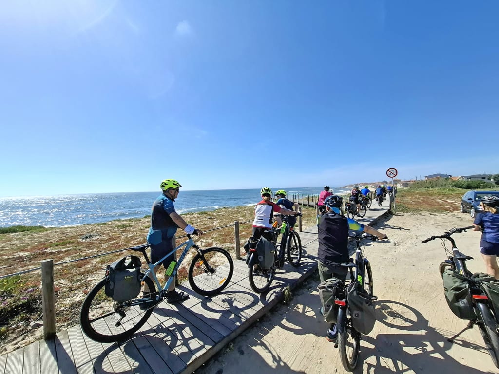 Ciclisti in sosta panoramica con biciclette davanti all’oceano Atlantico lungo la costa del Portogallo durante un viaggio in bici