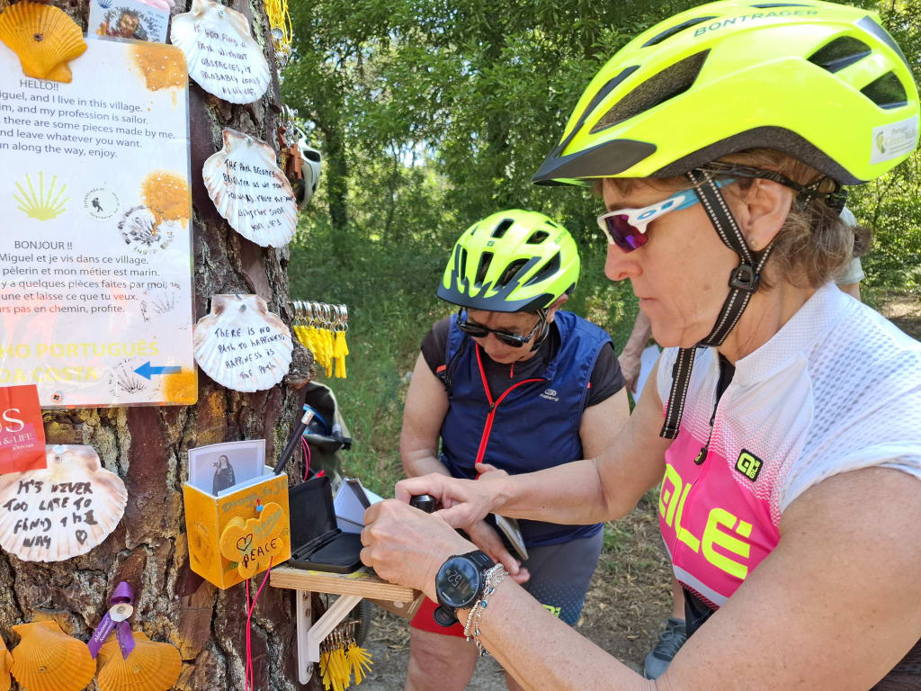 Viaggiatori in bici davanti alla bacheca con conchiglie simbolo del Cammino di Santiago lungo il Cammino Portoghese