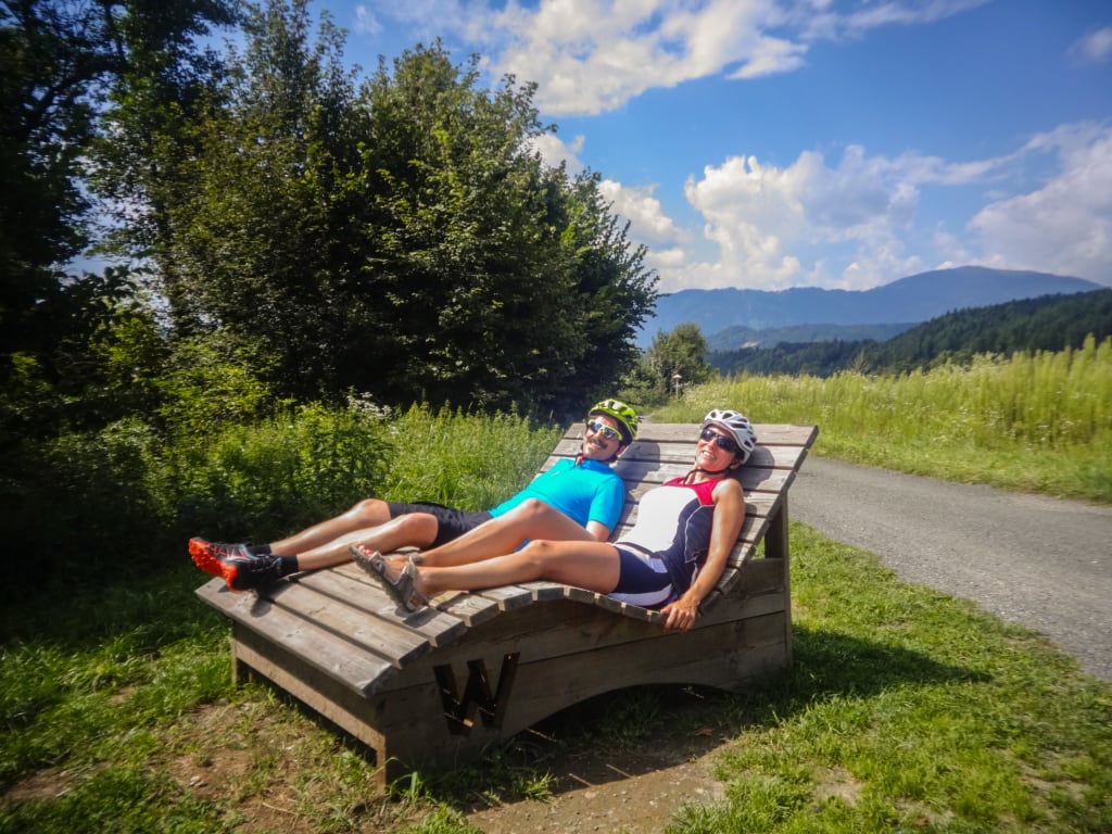 Coppia che si rilassa su lettini con vista sul lago Faaker See e sulle montagne, Carinzia.