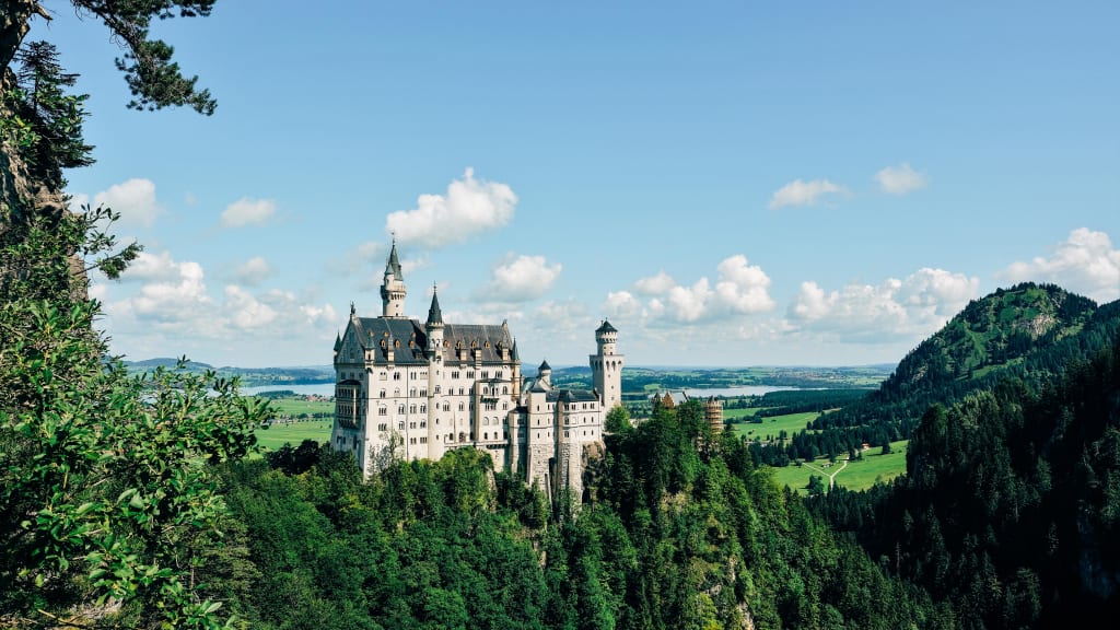 Veduta del castello di Neuschwanstein immerso nel verde, simbolo della Baviera e della Germania.