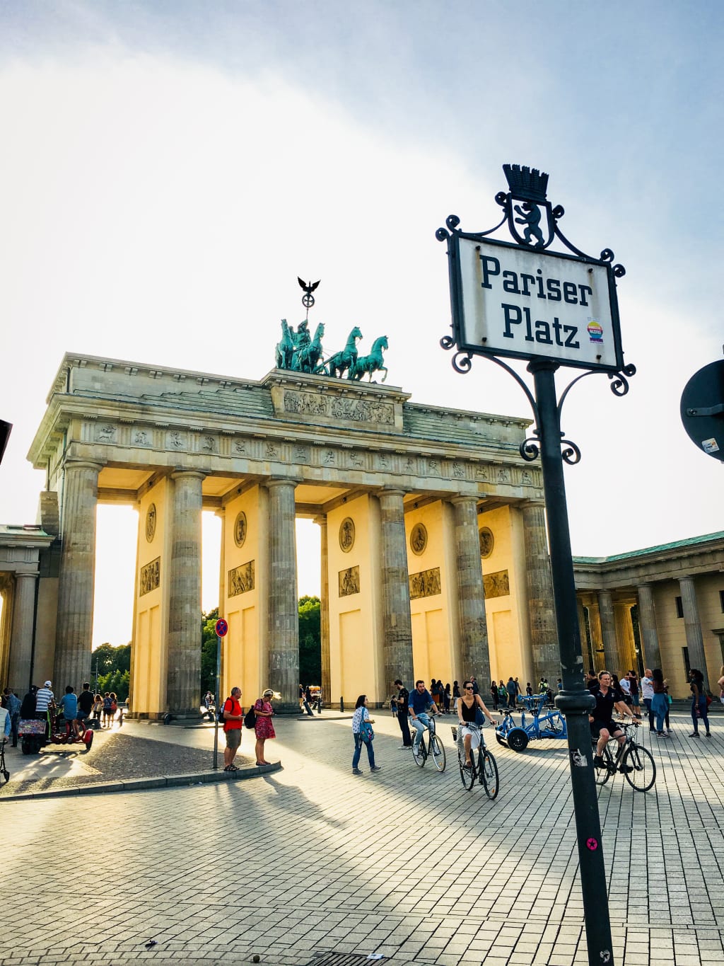 Ciclisti e pedoni davanti alla Porta di Brandeburgo, simbolo della città di Berlino.