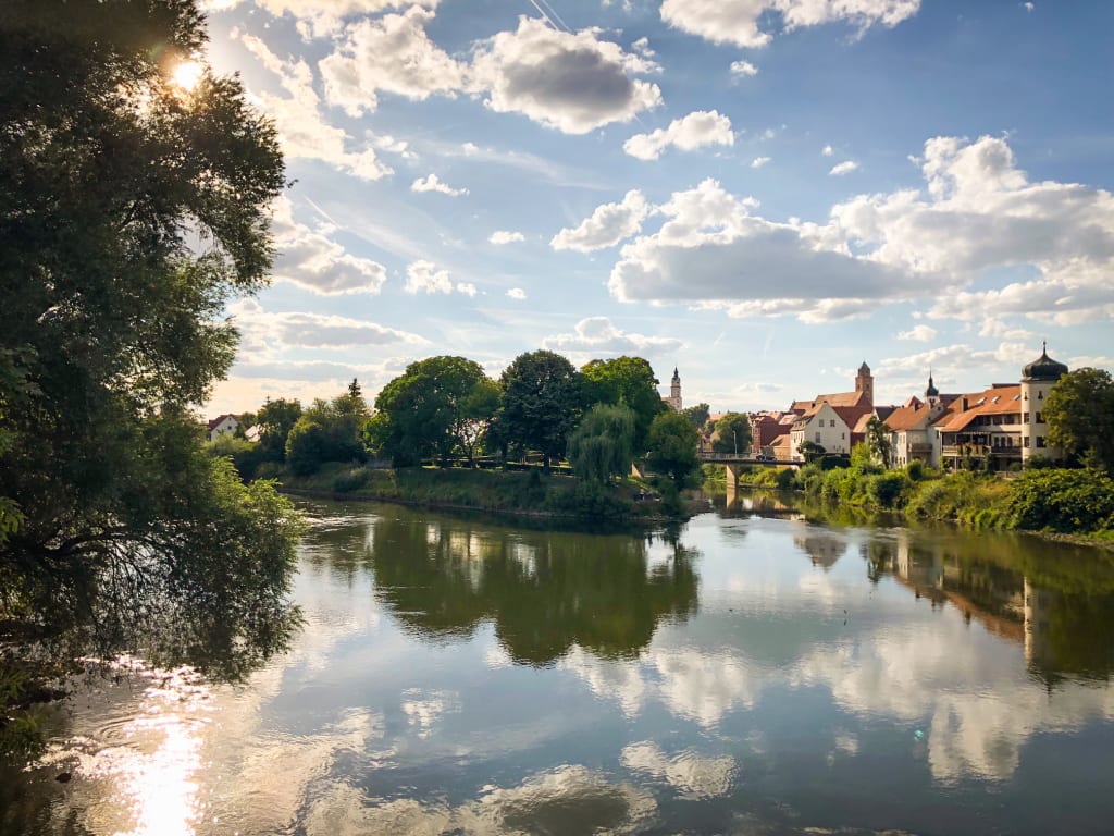 Fiume che riflette il cielo e il paesaggio nella cittadina di Dinkelsbühl, lungo la Romantische Strasse, Germania.