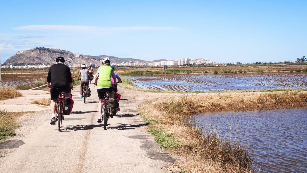 Cicloturisti lungo pista ciclabile nel Parco Naturale dell’Albufera di Valencia, tour in bici Girolibero