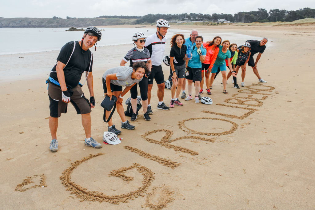 Gruppo di ciclisti sulla spiaggia che scrive Girolibero sulla sabbia, tour attivo in Bretagna