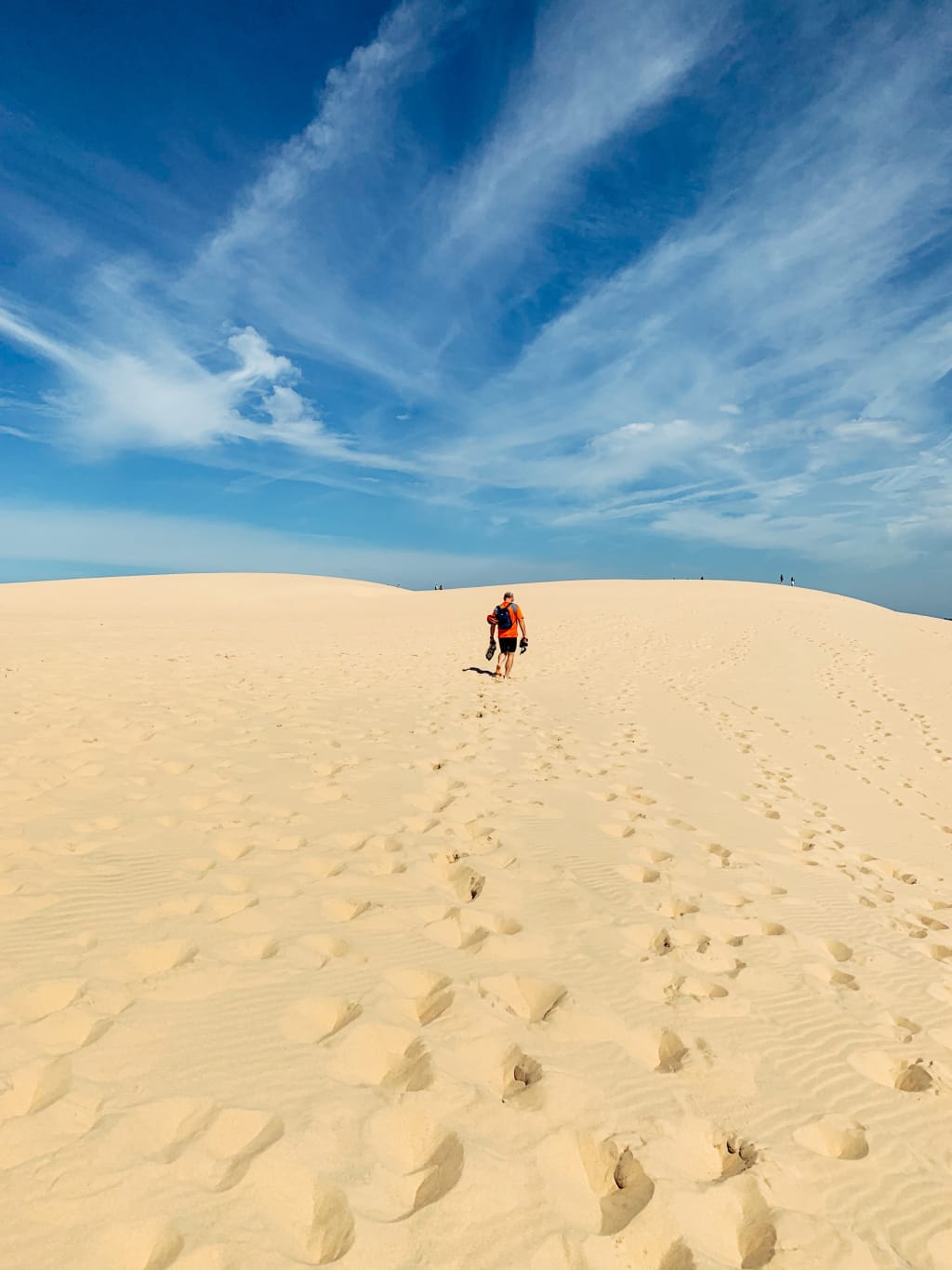Duna di sabbia dorata con una persona che cammina verso l'orizzonte, Bordeaux