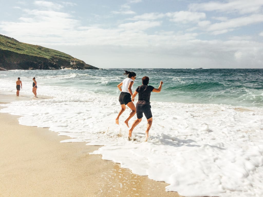 Famiglia che gioca tra le onde su una spiaggia sabbiosa in Cornovaglia.