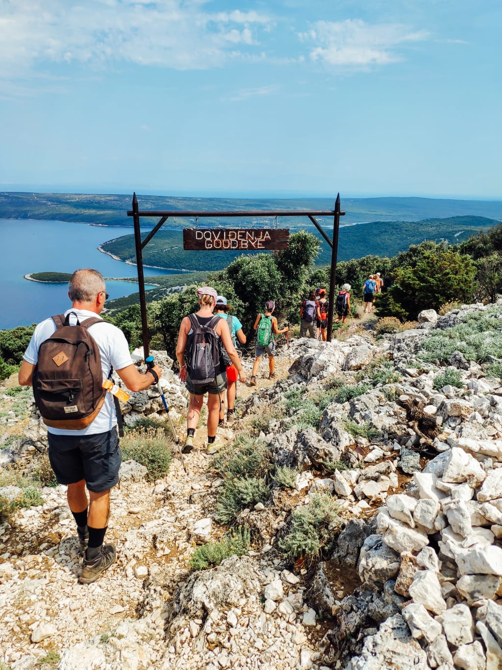 Escursionisti che esplorano un sentiero roccioso con il mare sullo sfondo, trekking in Croazia con "Girolibero"