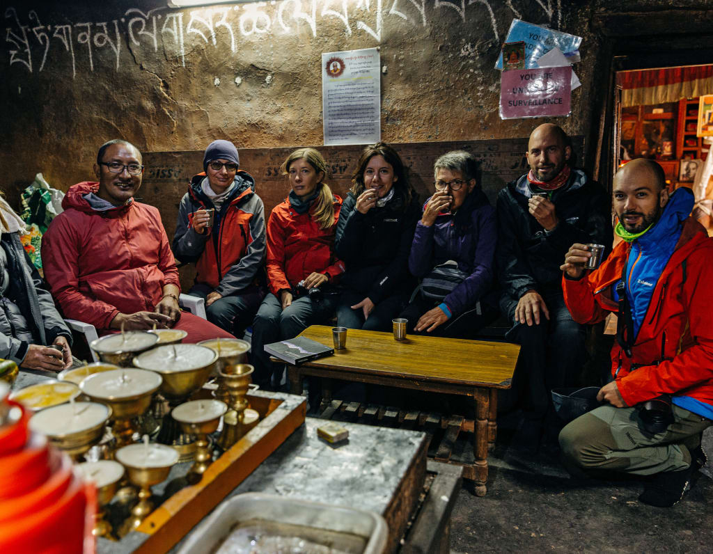 Monaci buddhisti e turisti seduti insieme durante un momento conviviale nel monastero nella valle di Spiti