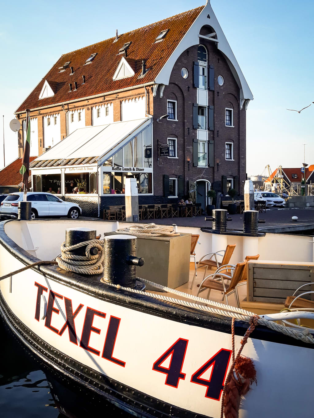 Traghetto storico "Texel" ormeggiato vicino a un edificio tradizionale in mattoni.