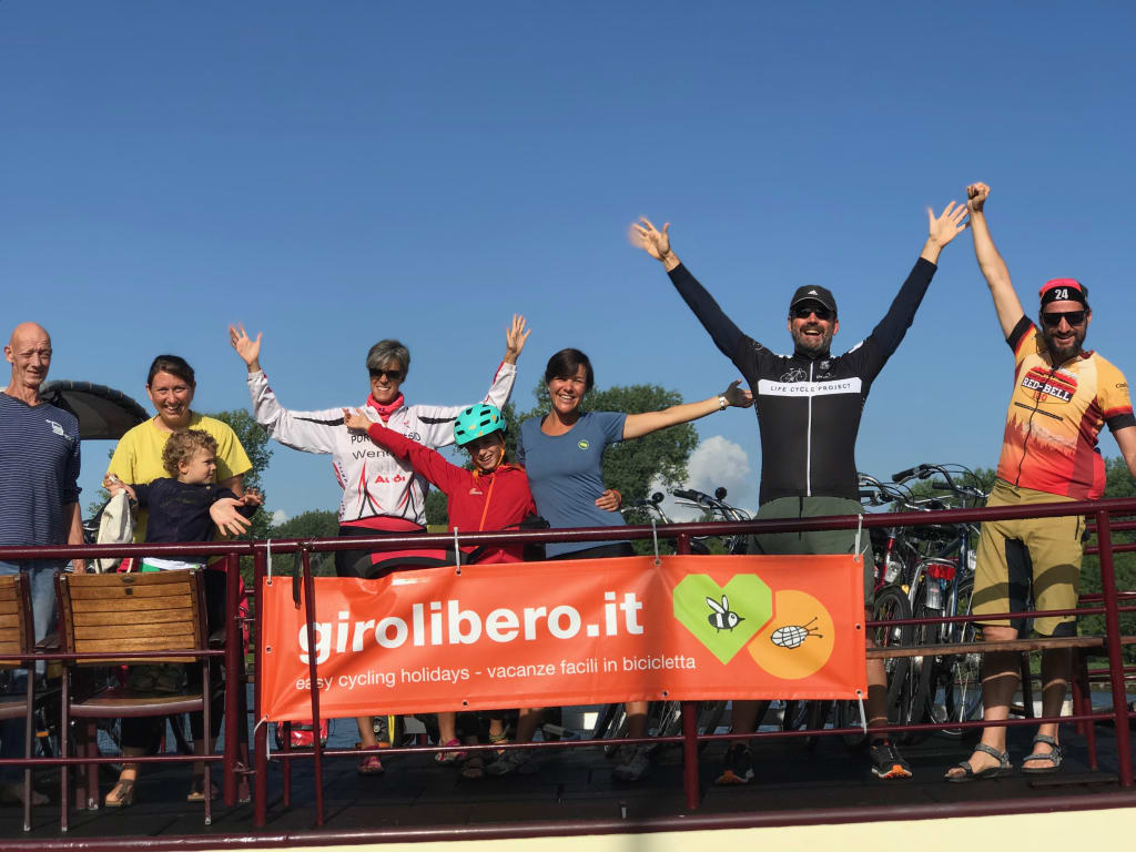 Gruppo di ciclisti con lo striscione “girolibero.it” salutano, viaggi in bici e barca organizzati