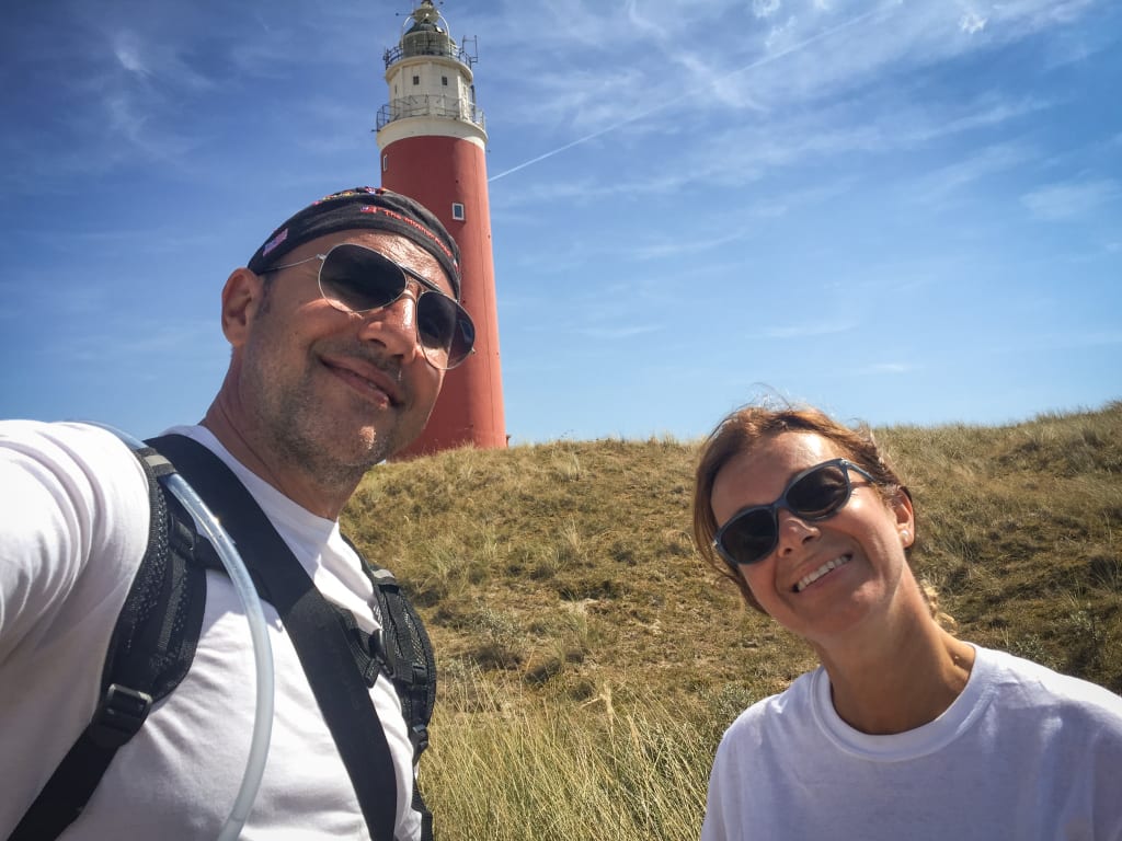 Coppia di turisti in viaggio con Girolibero che scatta un selfie davanti al faro di Texel