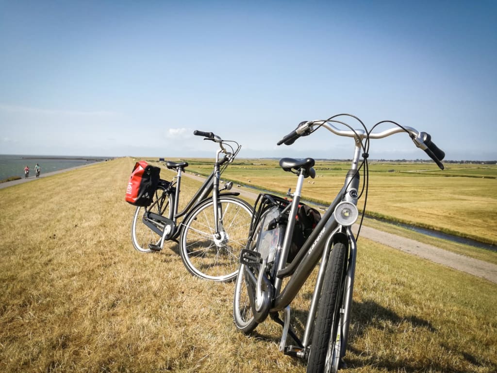 'Girolibero' bicycles resting on a grassy dune overlooking the sea, Frisian Islands