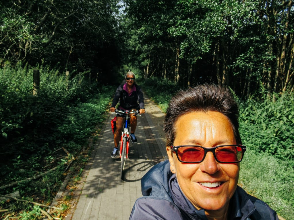 Ciclista su un sentiero immerso nel verde lungo la costa baltica, Polonia, pedalando lungo il Mar Baltico con "Girolibero"