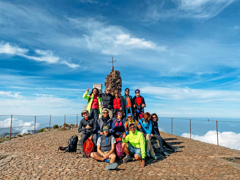 Gruppo di viaggiatori in posa su una scultura di rocce lungo la costa dell'Isola di Madeira, Portogallo.