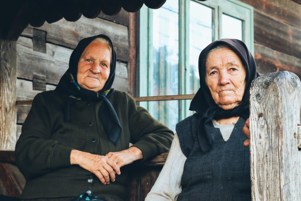 Anziane signore del Maramureș in abiti tradizionali sedute davanti a casa in legno, cultura e tradizioni rurali della Romania