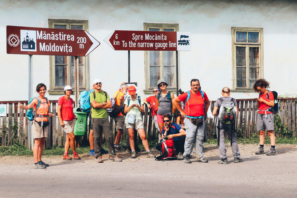 Gruppo di viaggiatori a un bivio segnaletico in un villaggio della Romania, escursione guidata