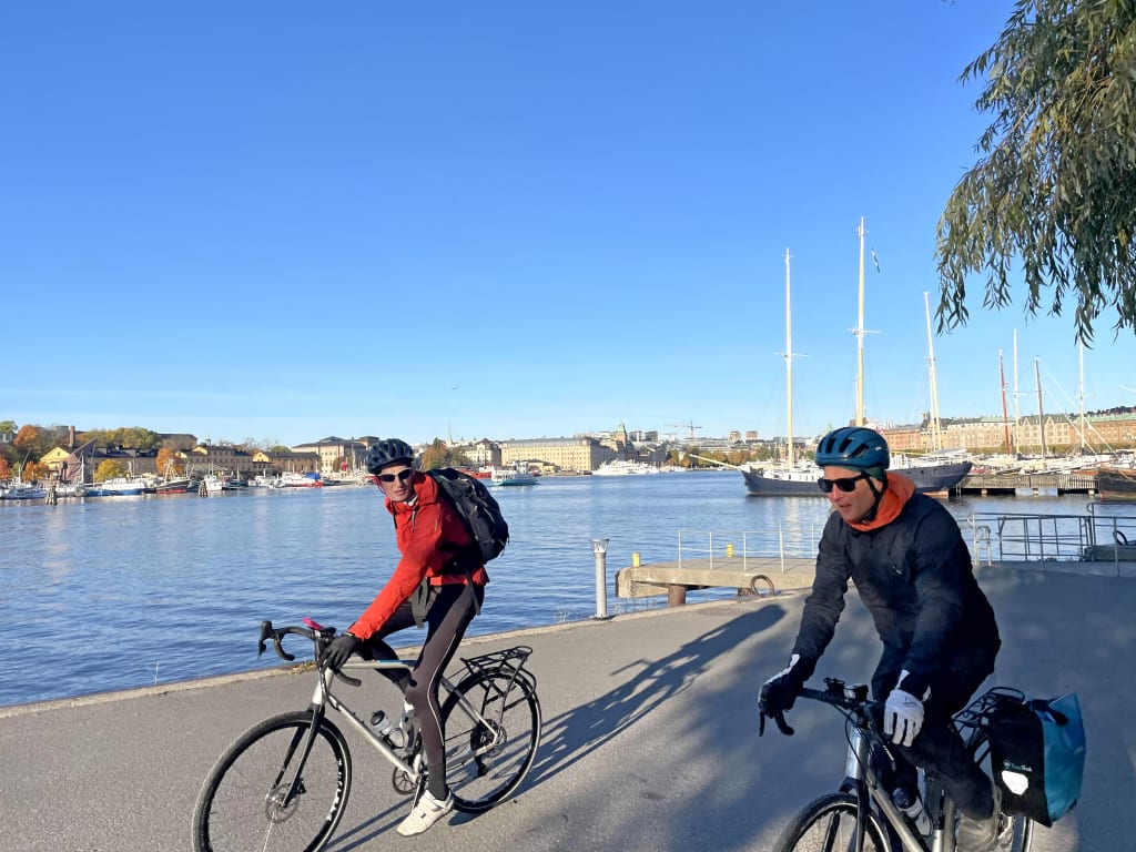 Coppia di cicloturisti lungo il lungolago di una città svedese.