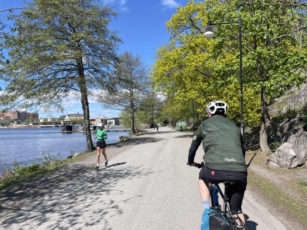 Ciclista su strada sterrata immersa nei boschi della Svezia, viaggio slow nella natura.