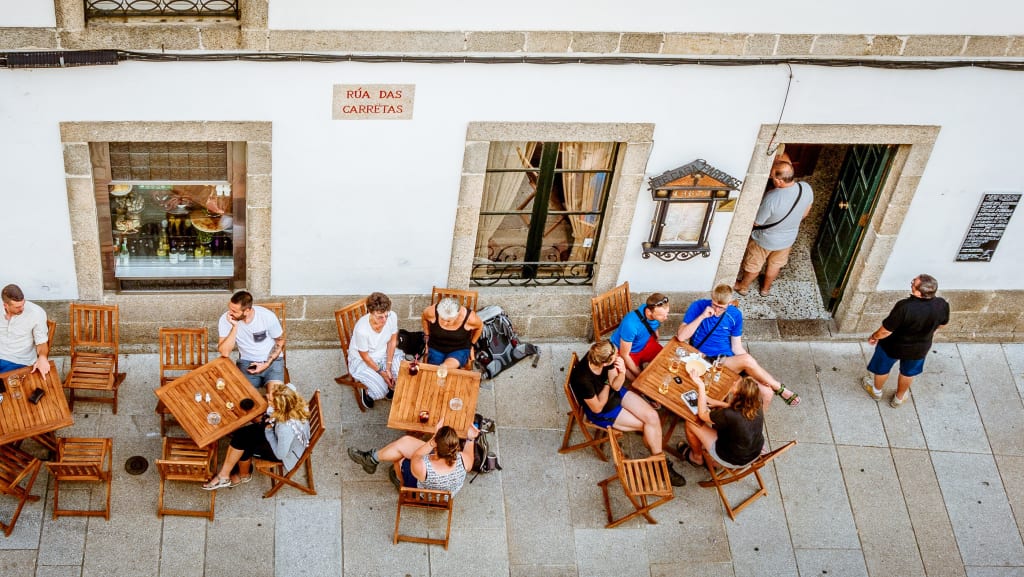 Pellegrini a Santiago seduti ai tavoli esterni di un locale nel centro di Santiago, Spagna