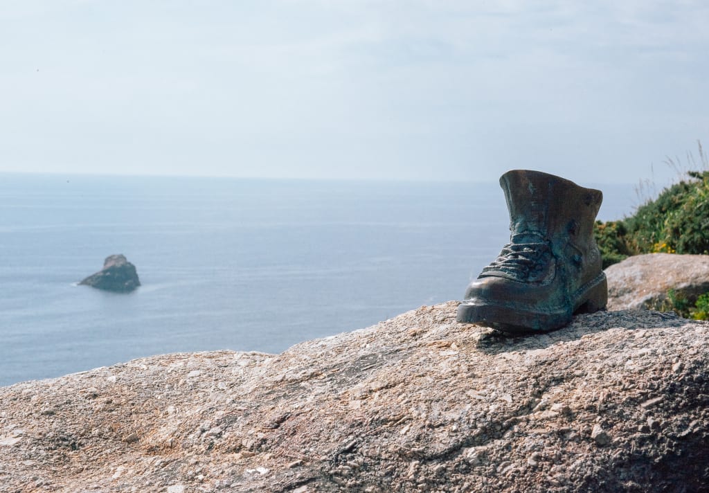 Scultura di uno scarpone in bronzo su una roccia sulla costa atlantica, Finisterre, Galizia