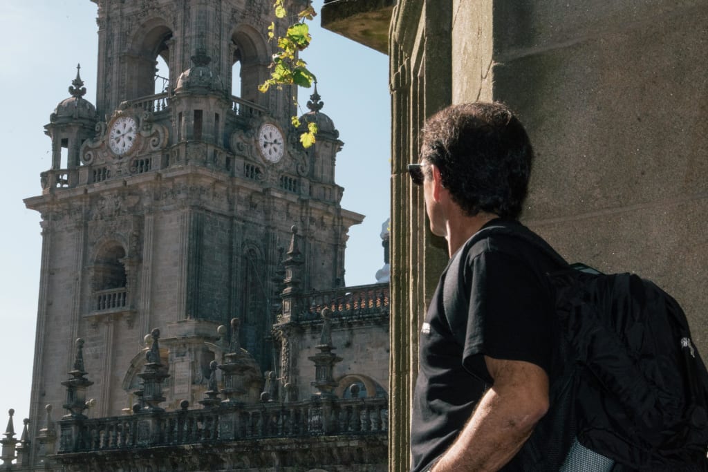 Un pellegrino ammira il campanile della cattedrale di Santiago, trekking in spagna lungo il Cammino di Santiago