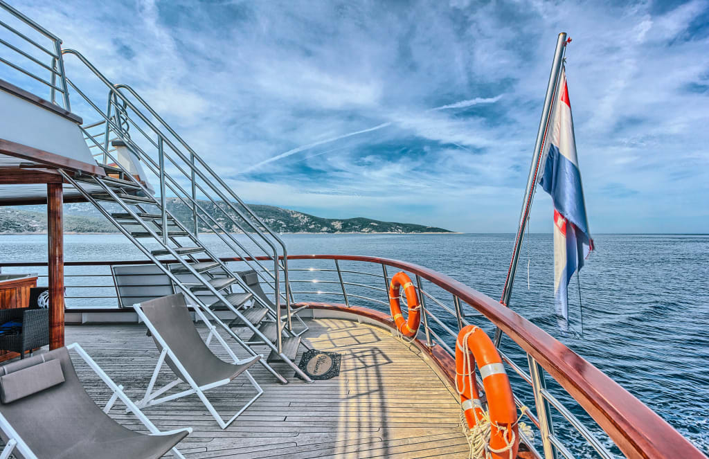 Ponte di una barca con salvagenti arancioni e bandiera croata su una crociera.