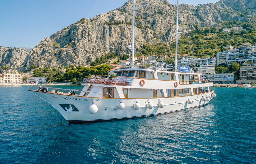 Barca da crociera "Romantica" su una baia vicino alla costa montuosa in Croazia.