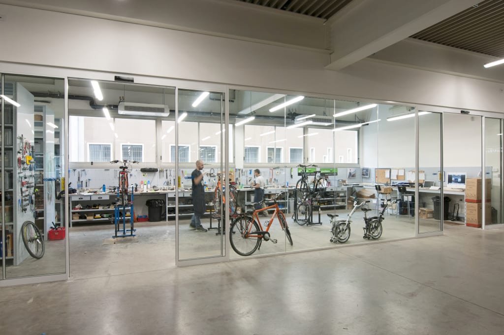 Maintenance workshop with orange bicycles, Girolibero
