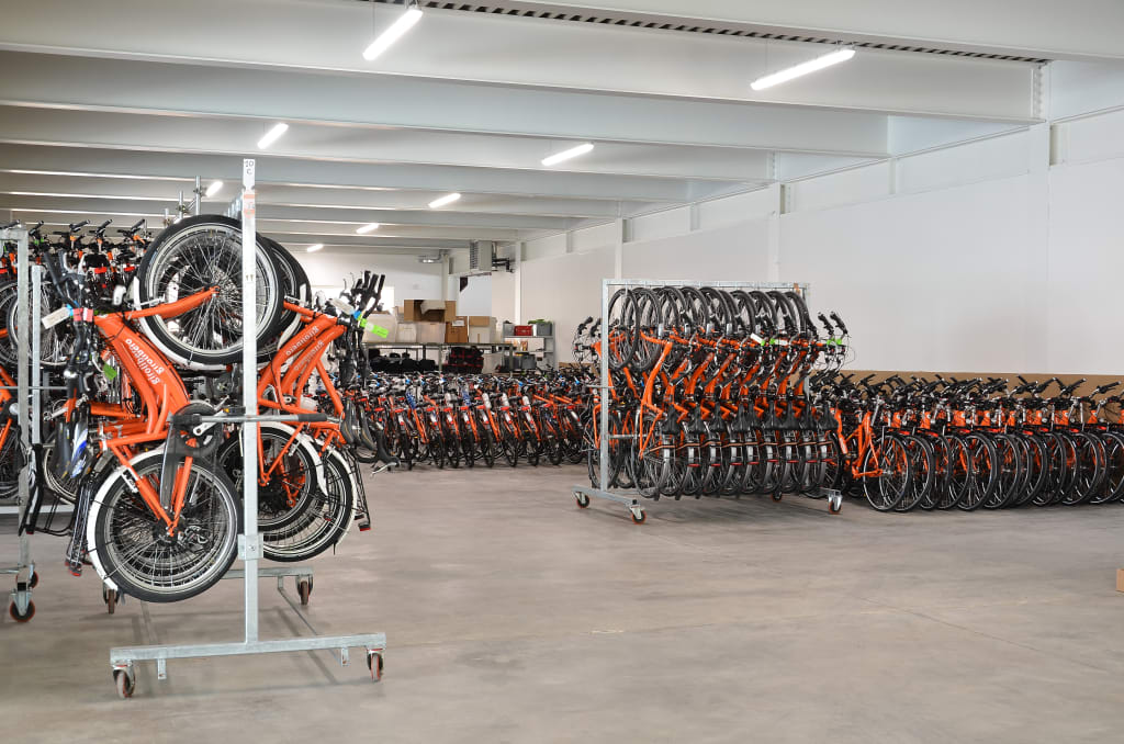 Warehouse with aligned Girolibero orange bicycles