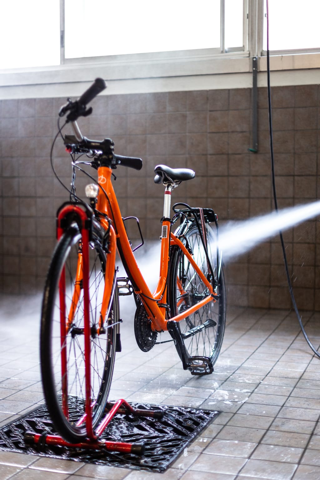 Thorough cleaning of an orange bicycle with water jet