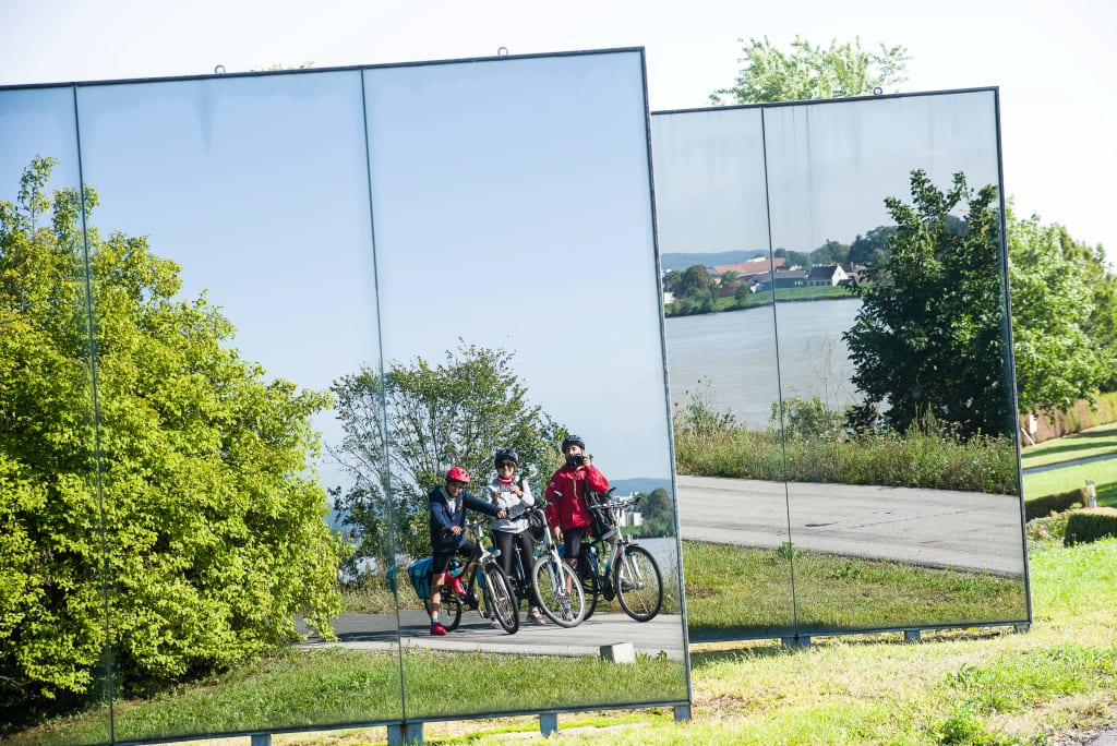 Cicloturisti fermi davanti a dei pannelli di vetro lungo il Danubio, vacanza in bici tra Linz e Vienna, Austria