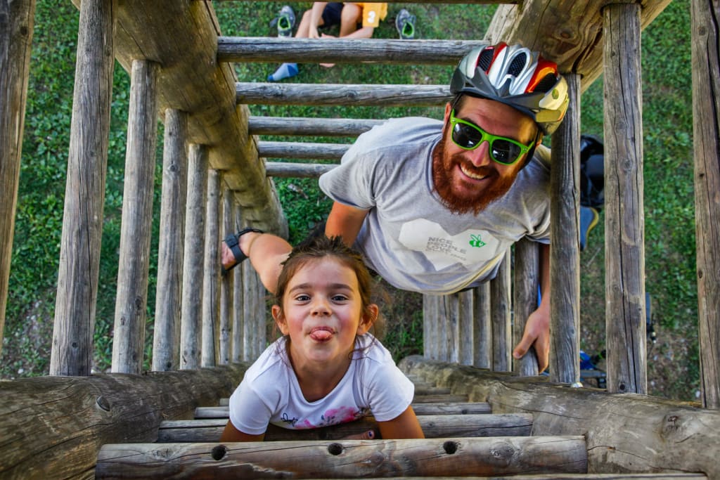 Padre e figlia sorridenti intenti ad arrampicarsi, divertimento, vacanza in famiglia all'aria aperta, ciclabile della Drava, Austria
