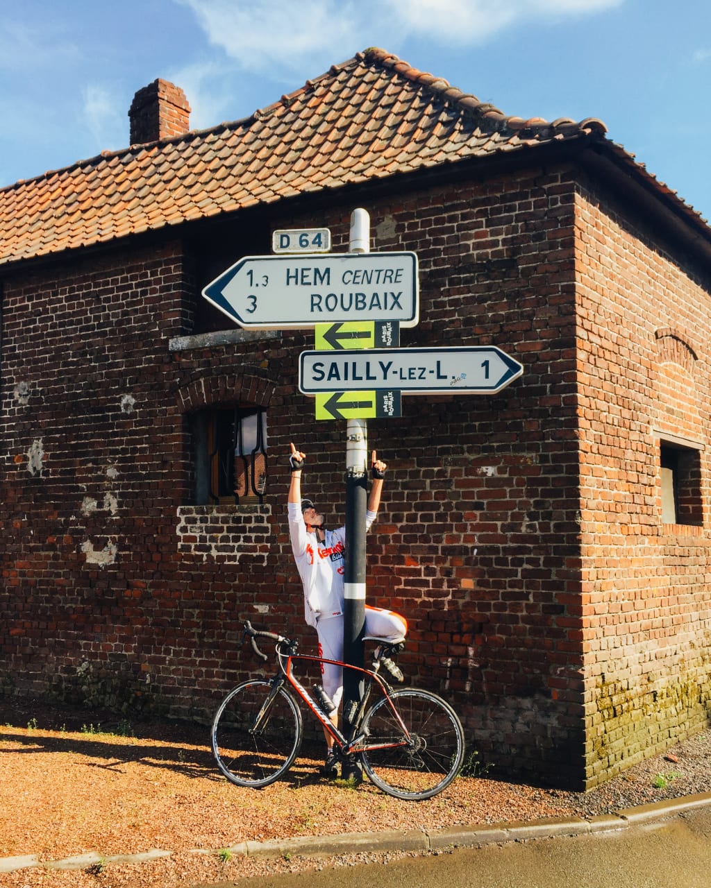 Ciclista davanti a un edificio in mattoni con segnaletica stradale, giro delle Fiandre in bici