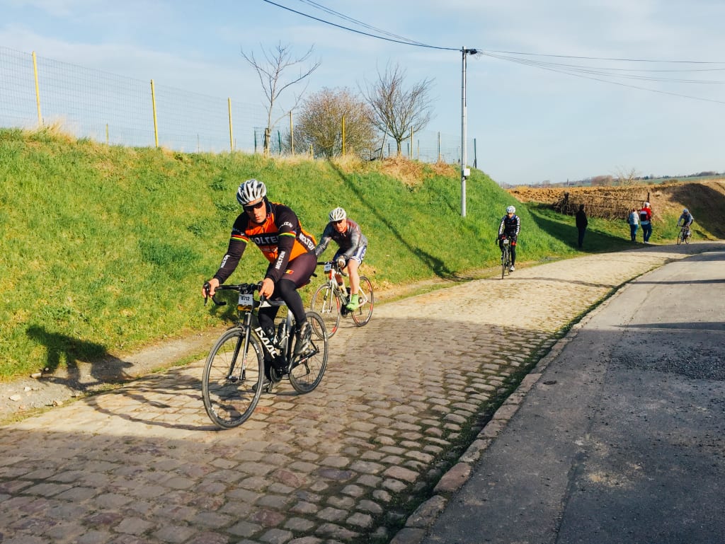 Ciclisti impegnati su una strada di pavé in un tratto rurale della Parigi-Roubaix.