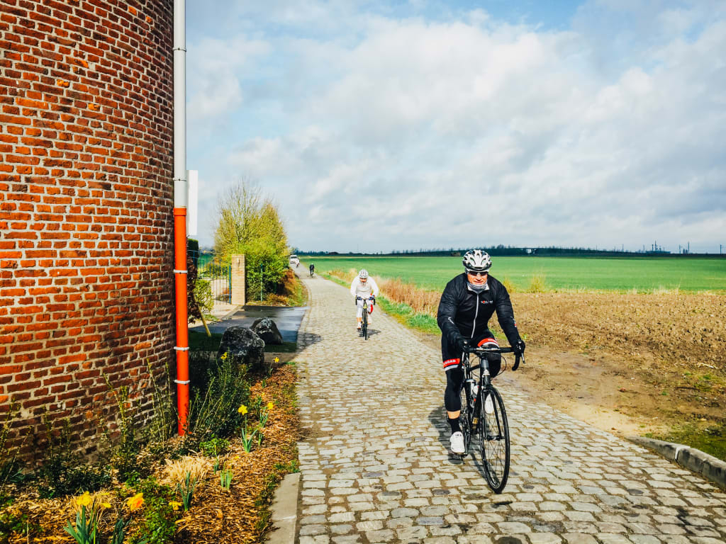 Ciclista su un tratto di pavé, accanto a un muro di mattoni, durante la gara di Roubaix.